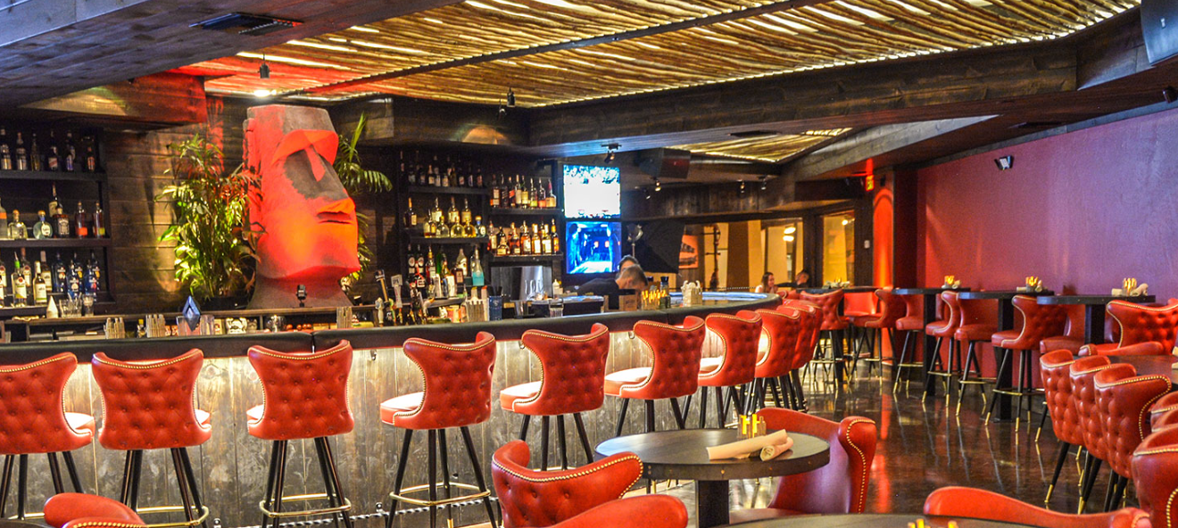 Bar with red chairs, stylish decor, and a TV behind the counter.