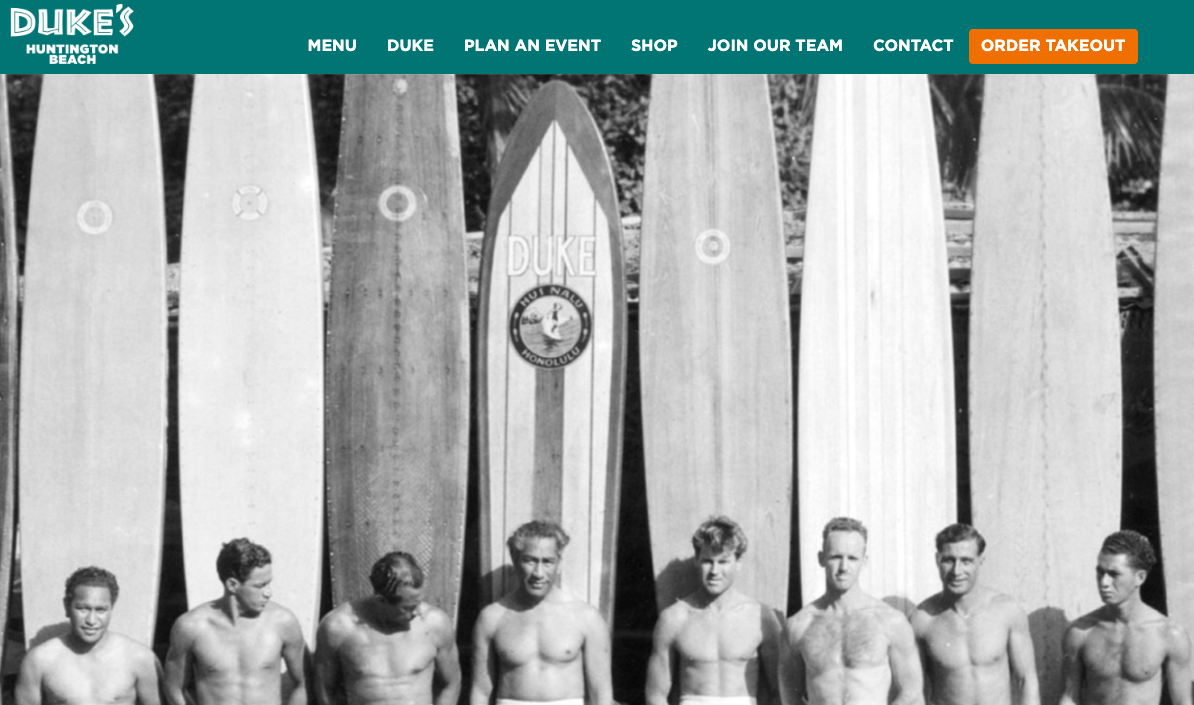 Row of men with vintage surfboards, black and white photo.