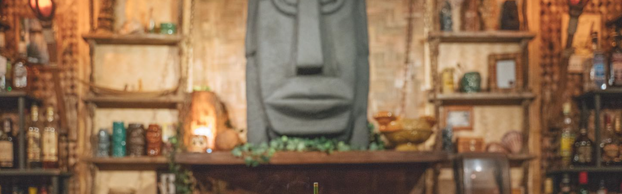 Large stone face sculpture surrounded by wooden shelves and vintage decor.