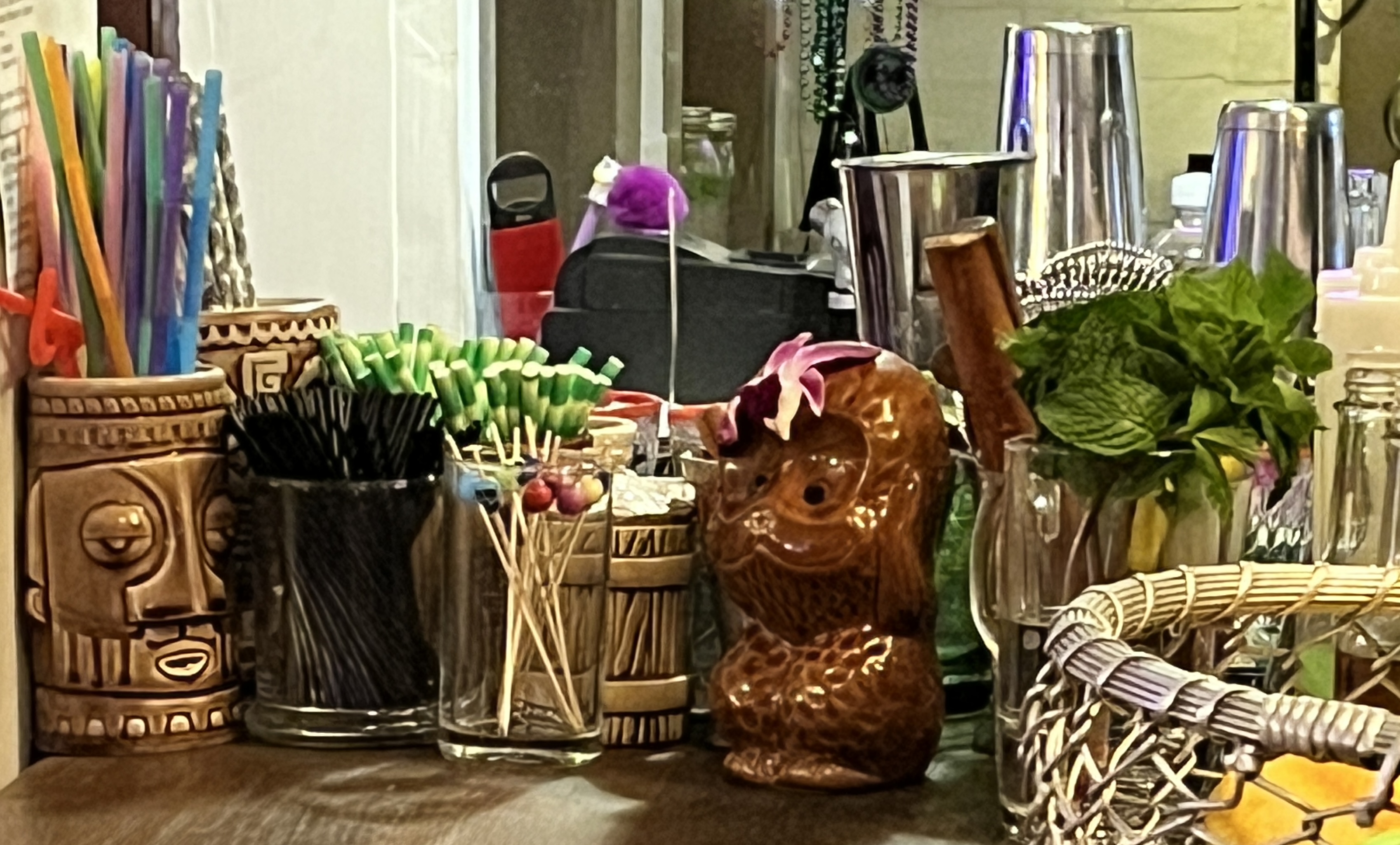Tiki bar tools and decorations on a wooden counter.