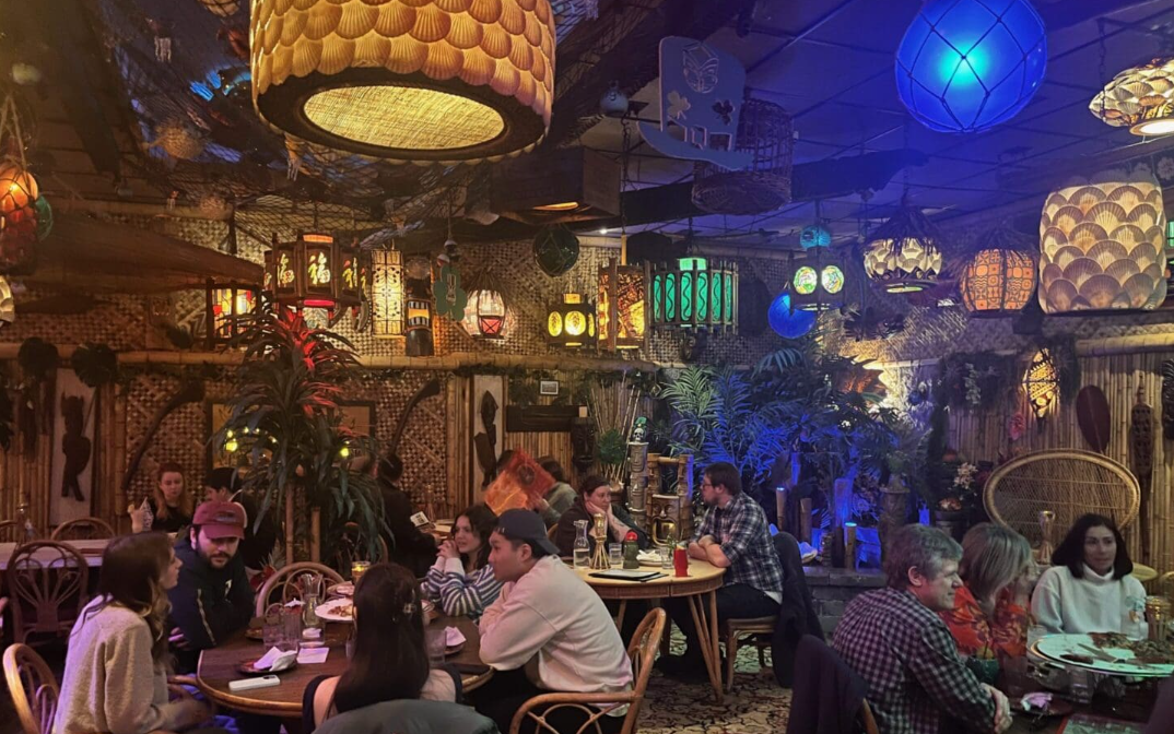 Dining area with colorful hanging lanterns and people at tables.