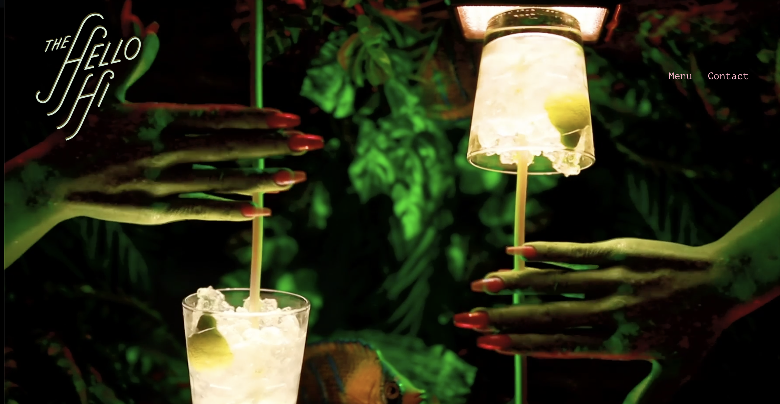 Two hands with long nails holding glowing cocktails in a dark, green-lit setting.