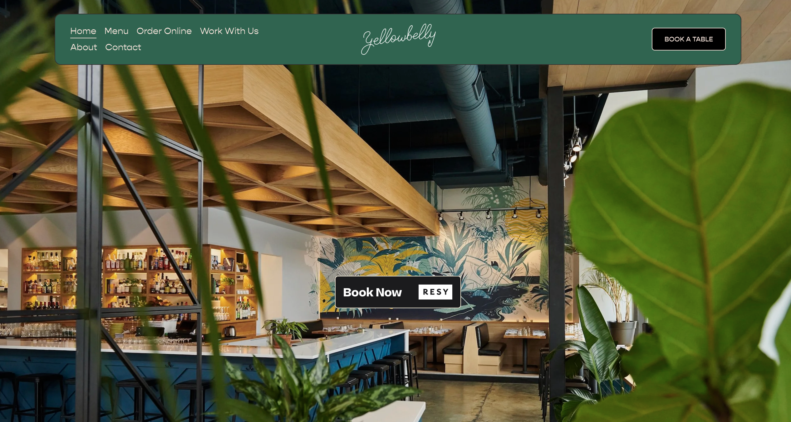 Modern restaurant interior with mural and plants.