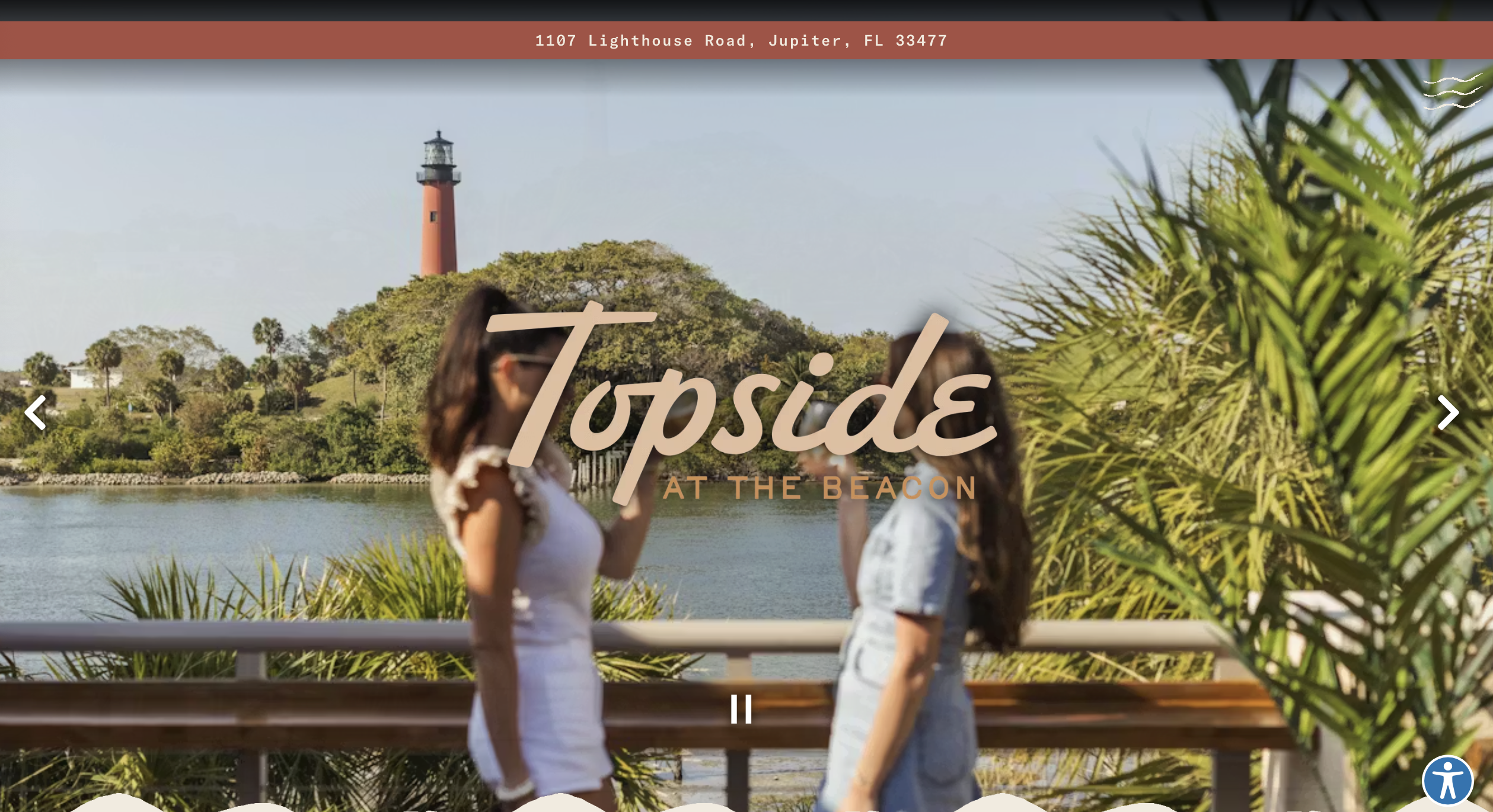 Two people on a deck with a lighthouse in the background.