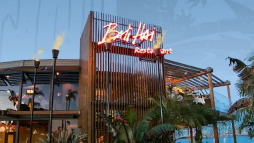 Tropical-themed restaurant with neon sign and palm trees.