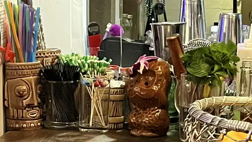 Tiki bar tools and decorations on a wooden counter.