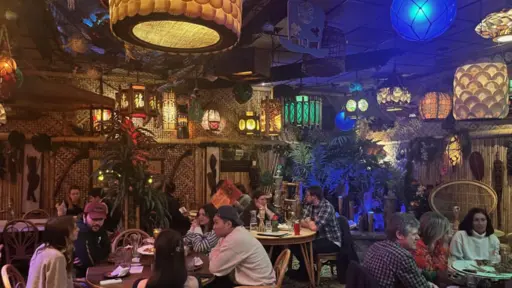 Dining area with colorful hanging lanterns and people at tables.