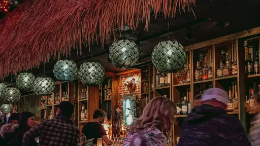 Dimly lit bar with hanging lanterns and people gathered at the counter.