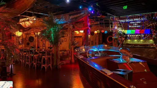 Tropical-themed bar with colorful lights and palm decor.