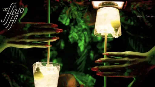 Two hands with long nails holding glowing cocktails in a dark, green-lit setting.