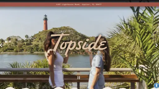 Two people on a deck with a lighthouse in the background.