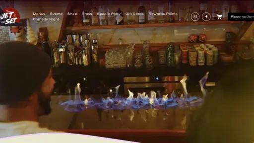 Bar with colorful lights and bottles, a person sits nearby.
