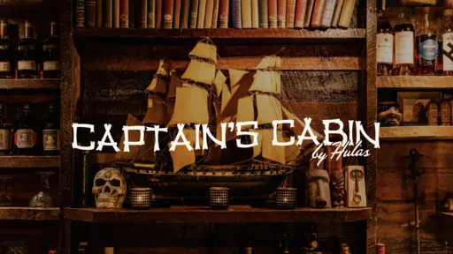 Model ship and skull on a wooden shelf with bottles and books.